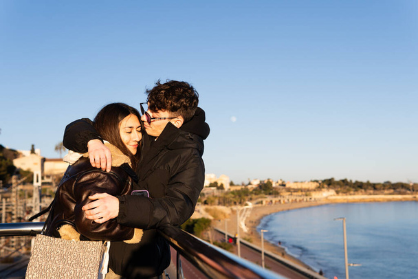 Pareja joven abrazándose en un balcón frente al mar - Foto, imagen