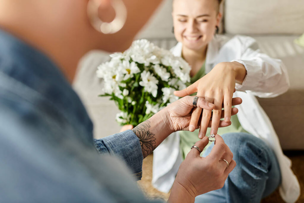 Ein rührender Moment, als eine Frau einem anderen liebevoll einen Ring an den Finger legt, der ihr Engagement und ihre Liebe symbolisiert. - Foto, Bild