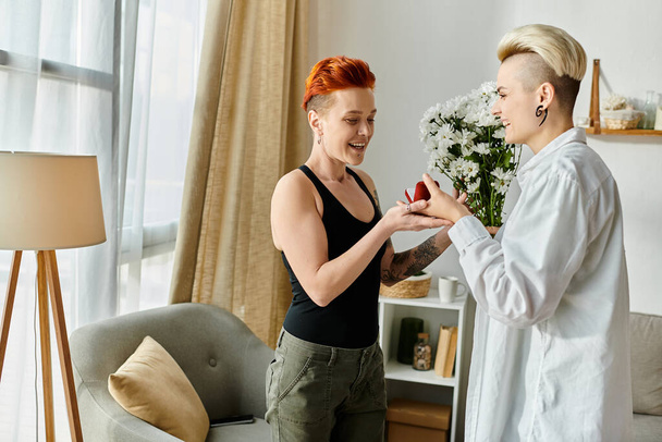 Two women with short hair happily exchanging gifts in a cozy living room setting. - Photo, Image