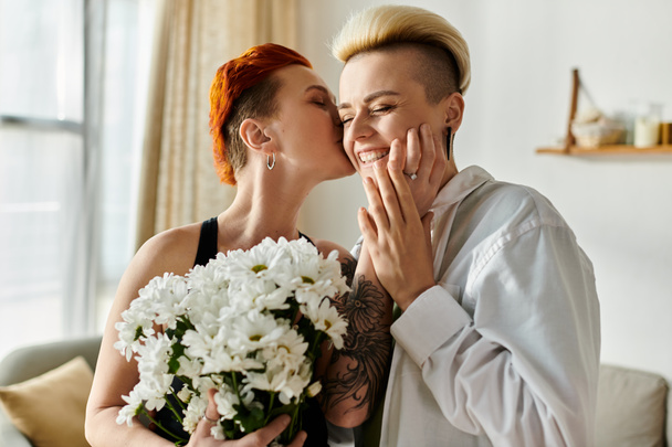 Two women with short hair embrace, hug, and kiss in a cozy living room, showing affection and love for each other. - Photo, Image