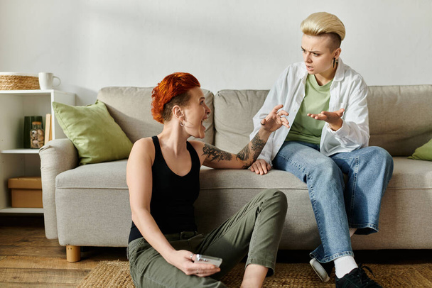 Dwie kobiety z krótkimi włosami siedzą na kanapie, pochłonięte emocjonalną rozmową - Zdjęcie, obraz