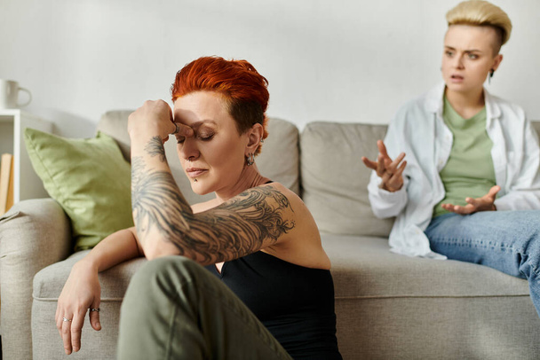 Due donne, una coppia lesbica con i capelli corti, si siedono su un divano, assorte nella conversazione - Foto, immagini