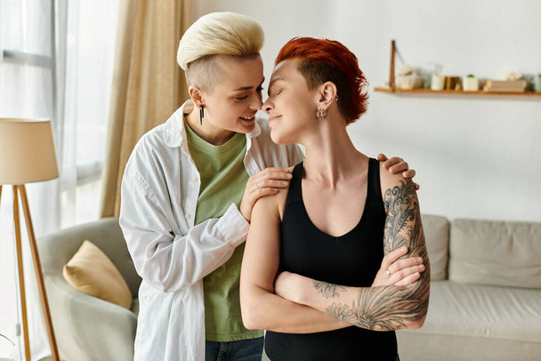Deux femmes, un couple lesbien aux cheveux courts, s'embrassent tendrement dans leur salon douillet, mettant en valeur l'amour et l'unité. - Photo, image