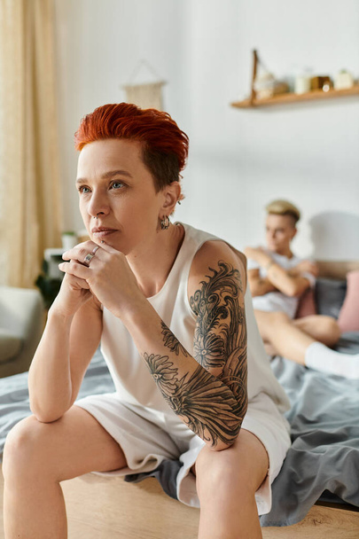 A woman with fiery red hair sits on a bed. - Photo, Image