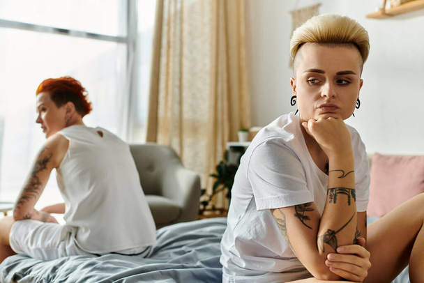 Dvě ženy s tetováním, lesbický pár, sedí spolu na posteli v ložnici, předvádí problémy ve vztahu - Fotografie, Obrázek