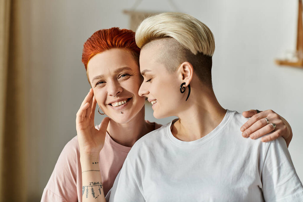 Una coppia lesbica con la testa rasata colpisce una posa sicura in una camera da letto, abbracciando il loro stile unico e celebrando il loro stile di vita LGBT. - Foto, immagini