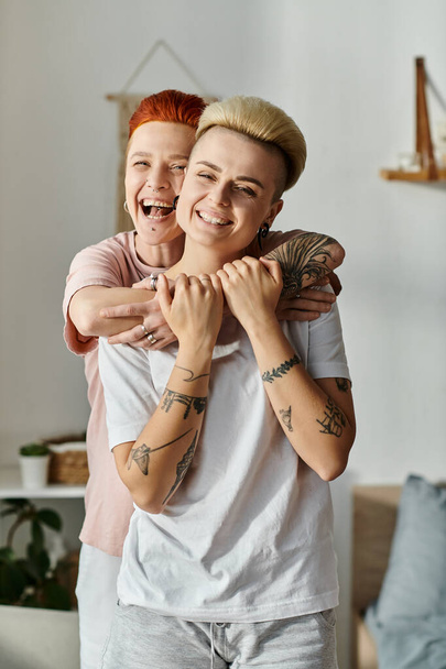 Dos mujeres con el pelo corto compartiendo un abrazo sincero en una acogedora sala de estar, expresando amor y conexión. - Foto, Imagen
