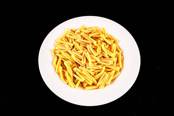 A plate of pasta is on a white plate. The pasta is yellow and looks like it is cooked - Photo, Image