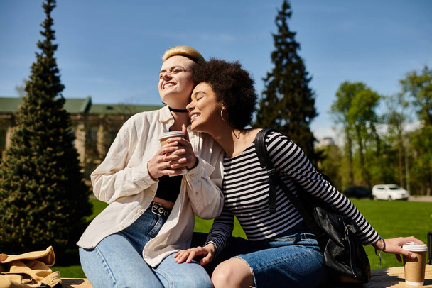 Ένα ζευγάρι νεαρών γυναικών που απολαμβάνουν μια ειρηνική στιγμή σε ένα παγκάκι στο πάρκο. - Φωτογραφία, εικόνα