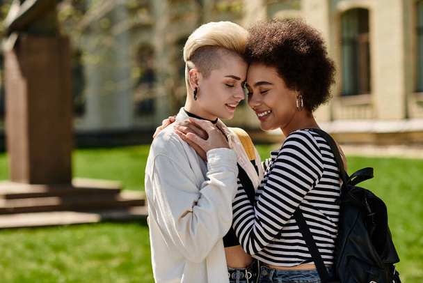 Két fiatal nő, leszbikus pár, egy meleg ölelést osztanak meg a természettel körülvéve egy békés parkban.. - Fotó, kép