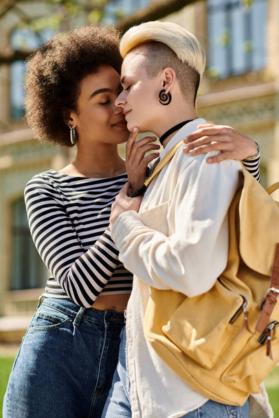 мультикультурная лесбийская пара, обнимающая друг друга перед зданием университета. - Фото, изображение