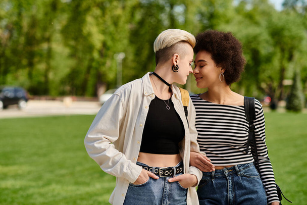 Мультикультурная лесбийская пара, обе молодые студентки, стильно прогуливаются в парке рядом с университетским кампусом. - Фото, изображение
