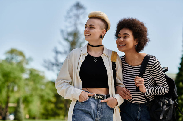 Zwei junge Frauen, ein multikulturelles lesbisches Paar, gehen gemeinsam in einem Park spazieren - Foto, Bild