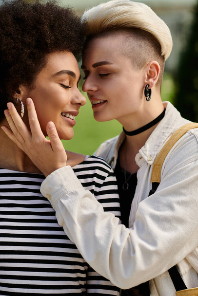 Um casal lésbico multicultural compartilha um abraço afetuoso em um parque, exibindo amor, apoio e conexão. - Foto, Imagem