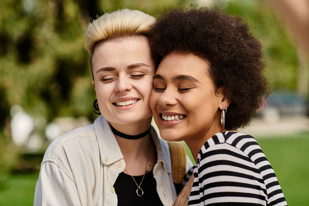 Dos mujeres jóvenes con un atuendo elegante compartiendo un abrazo sincero en un entorno vibrante parque. - Foto, imagen