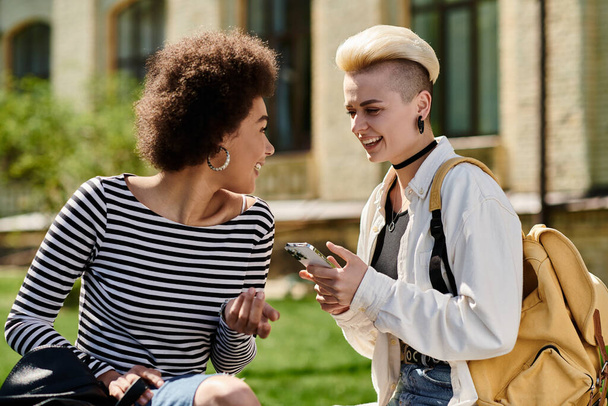 Due giovani donne in un parco, assorte in telefonate separate, che si connettono con i propri cari o amici. - Foto, immagini