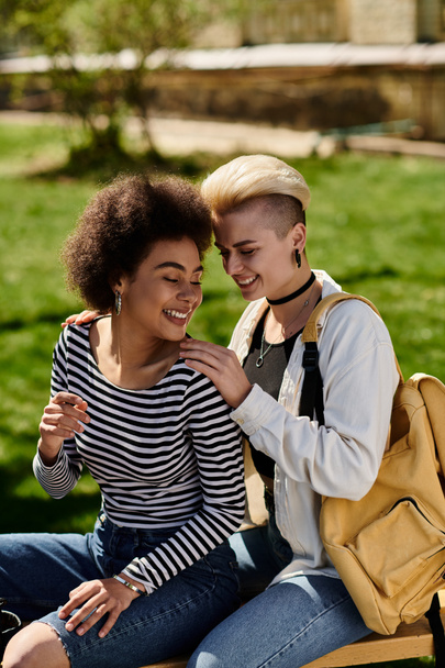İki genç kadın, lezbiyen çift, parktaki bir bankta huzur içinde oturuyorlar, yemyeşil ve doğanın sesleriyle çevrili.. - Fotoğraf, Görsel