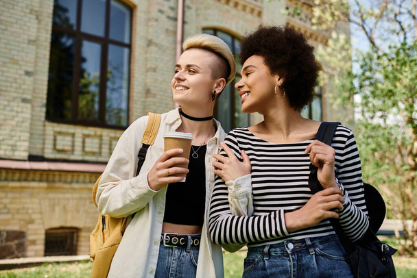 Casal lésbico multicultural, jovens estudantes do sexo feminino, ficar em frente a um edifício em um campus universitário. - Foto, Imagem