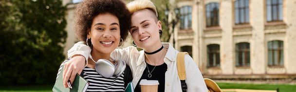 Twee jonge vrouwen, lesbisch stel, stijlvol poseren voor een universiteitsgebouw. - Foto, afbeelding