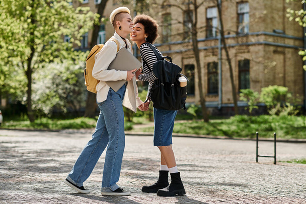 Két fiatal nő, egy multikulturális leszbikus pár, egy egyetemi campus melletti városi utcában beszélgetnek.. - Fotó, kép