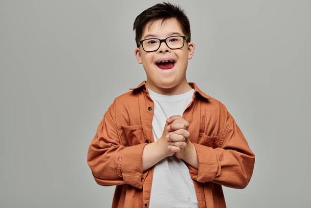 Un petit garçon avec trisomie 21, lunettes de sport, sourit vivement. - Photo, image
