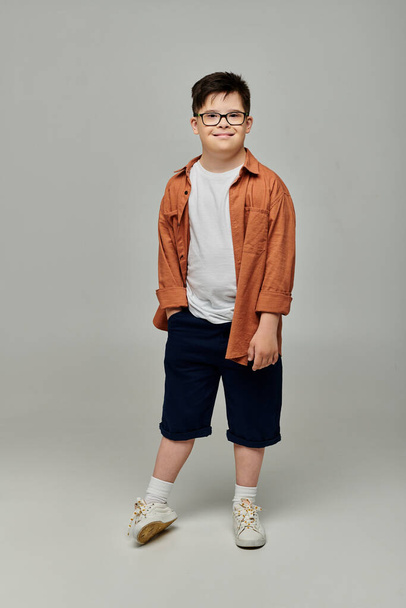 Симпатичный мальчик с синдромом Дауна в очках и шортах позирует для портрета - Фото, изображение