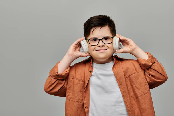 bambino con sindrome di Down con occhiali ascoltare musica. - Foto, immagini