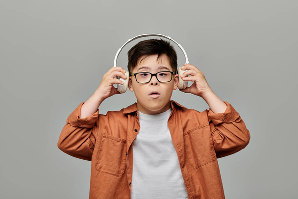 A boy with Down syndrome with glasses immerses in music through headphones. - Photo, Image