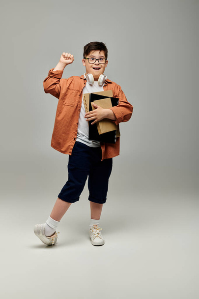 Маленький мальчик с синдромом Дауна держит книги и позирует. - Фото, изображение