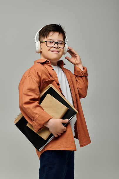 Kleiner Junge mit Down-Syndrom trägt Kopfhörer und hält Notizbücher. - Foto, Bild