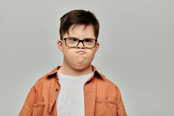 Mały chłopiec z zespołem Downa w okularach, pokazujący swoją zabawną i złośliwą stronę.. - Zdjęcie, obraz