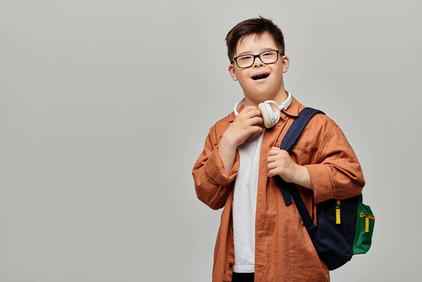 Ένα αγόρι με σύνδρομο Down που φοράει γυαλιά και ένα σακίδιο. - Φωτογραφία, εικόνα