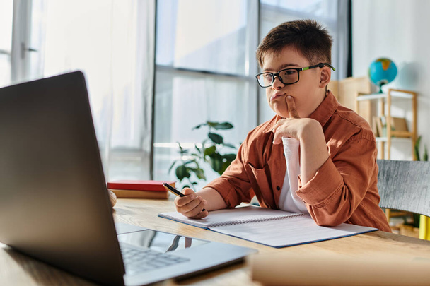 Niño pequeño con síndrome de Down con estudios de gafas en el portátil en el escritorio. - Foto, Imagen