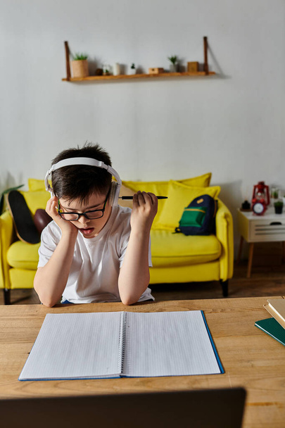 A Down-kóros fiú fejhallgatót visel, otthon jegyzetfüzetbe ír.. - Fotó, kép