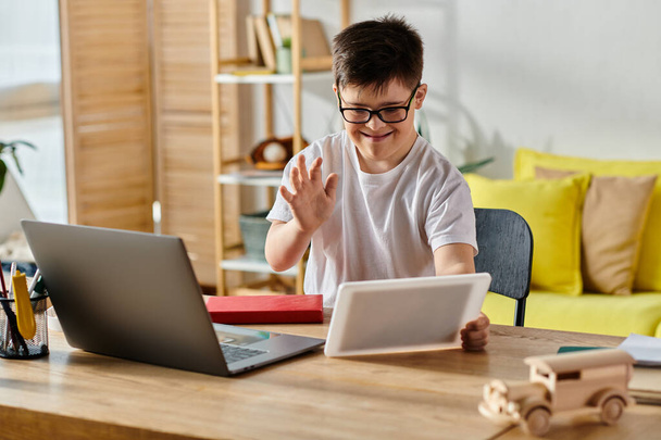 Un niño adorable con síndrome de Down absorto en el uso de una computadora portátil en casa. - Foto, Imagen