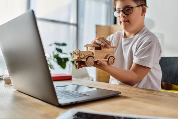 Down sendromlu sevimli çocuk oyuncak araba ve dizüstü bilgisayarla oynuyor.. - Fotoğraf, Görsel