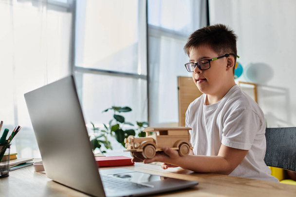 entzückender Junge mit Down-Syndrom spielt zu Hause kreativ mit Holzspielzeug am Laptop. - Foto, Bild