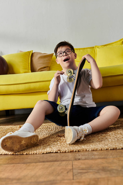 Un adorable garçon avec le syndrome de Down assis par terre avec une planche à roulettes. - Photo, image