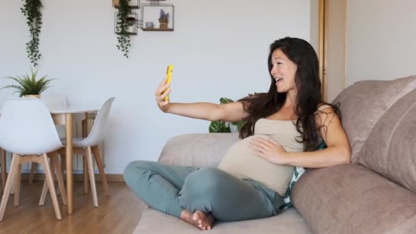Slow motion video of an asian pregnant mother doing a video call with the mobile at home - Footage, Video