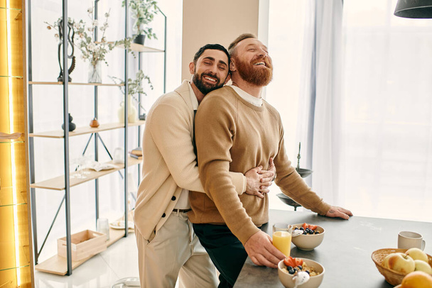 Deux hommes heureux, un couple gay, embrasser dans un câlin chaleureux dans une cuisine moderne, mettant en valeur leur amour et leur lien. - Photo, image