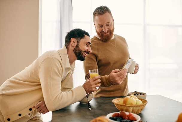 Δύο άνδρες απολαμβάνουν το πρωινό μαζί σε μια σύγχρονη κουζίνα, μοιράζονται μια στιγμή αγάπης και σύνδεσης. - Φωτογραφία, εικόνα