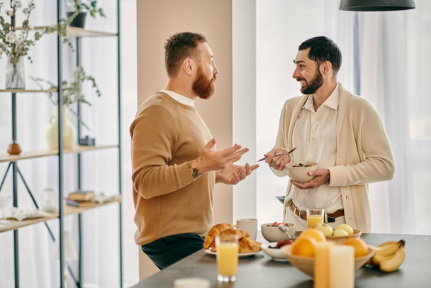Dos hombres gay felices charlando en una cocina moderna, discutiendo opciones de desayuno y disfrutando de la compañía de los demás. - Foto, imagen