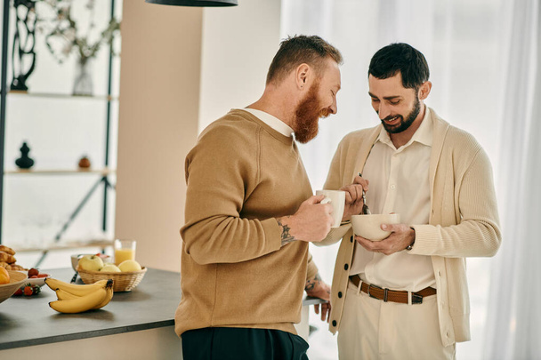Due uomini, una coppia gay felice, in piedi in una cucina moderna, impegnati in una vivace conversazione. - Foto, immagini