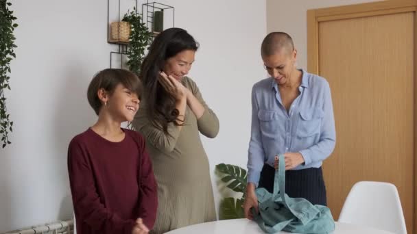 Slow motion video van een niet-reglementaire familie op het punt om bevallen opgewonden voor te bereiden babykleding in een zak - Video