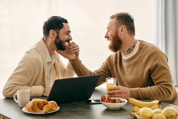 A joyful gay couple engaged in deep conversation while seated at a table in a cozy modern apartment. - Fotografie, Obrázek