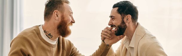 Two men with beards engage in an animated conversation in a modern apartment, showcasing the bond and connection between them. - Photo, Image