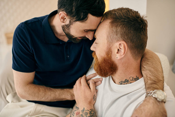 Двоє чоловіків, щаслива гомосексуальна пара, обіймають один одного на дивані в сучасній вітальні. - Фото, зображення