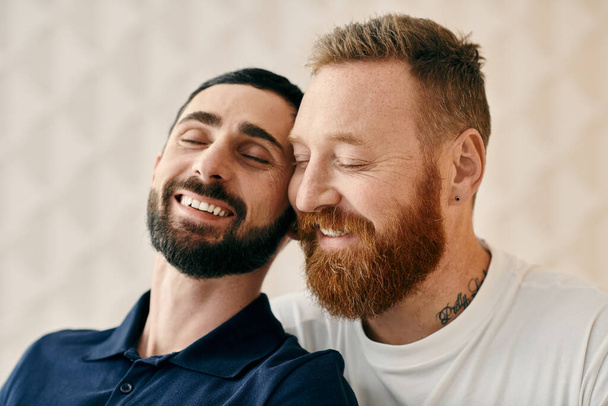 Two men with beards, one in a blue shirt and the other in a striped shirt, are smiling warmly at each other in a cozy living room. - Fotoğraf, Görsel