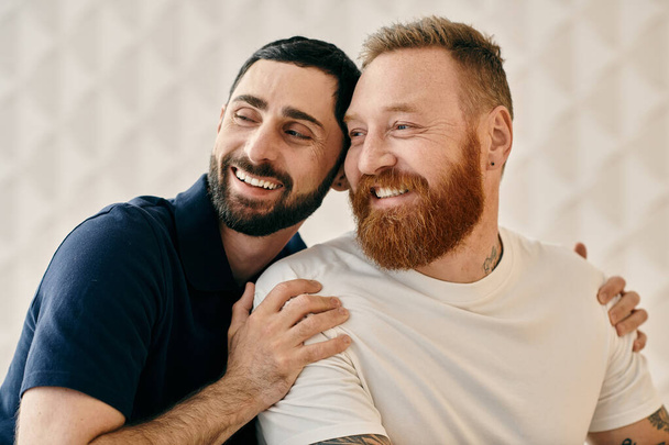 Двоє бородатих чоловіків, щасливих і закоханих, щільно обіймаються у сучасній вітальні. - Фото, зображення