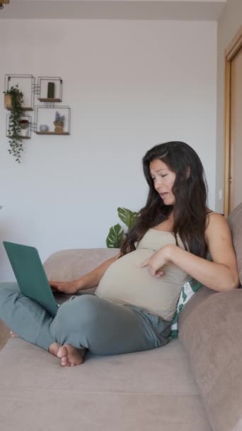 Vertical slow motion video of a serious pregnant woman making a video call with the laptop at home - Footage, Video